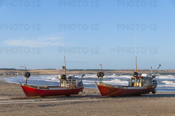 Two red fishing boats lie on the beach of the Atlantic Ocean