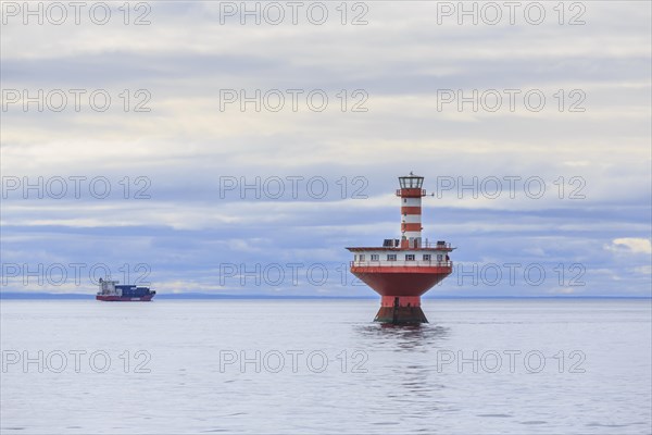 Lighthouse Phare du Haut-Fond Prince in Saint Lawrence River with freighter in the back