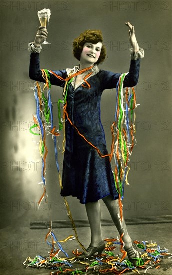 Woman celebrates New Year's Eve with champagne and paper snakes