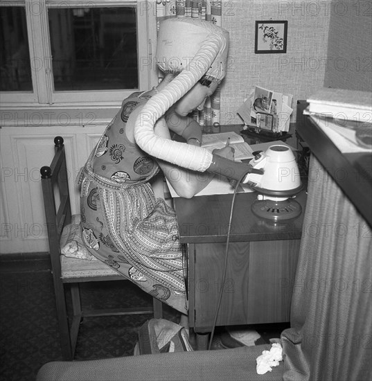 A woman dries her hair at the desk