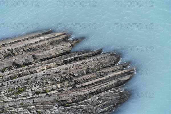 Glacial smooth-cut rock juts out into turquoise-blue Lake Argentino