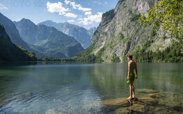 Young man stands on a stone in lake Obersee