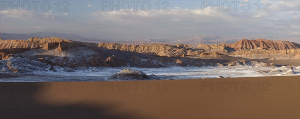 Giant dunes and bizarre red rock formations with white salt at sunset