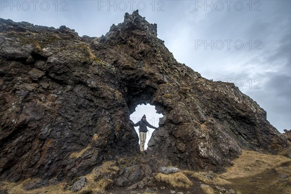 Young man stands in rock arch
