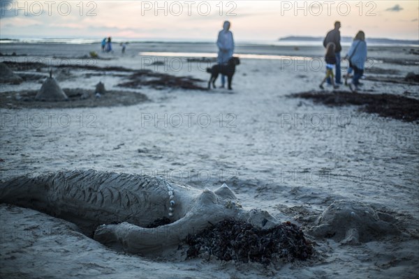 Mermaid of sand and strollers at dusk on the beach