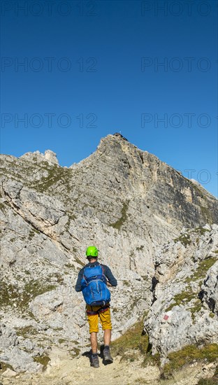 Hiker with climbing helmet on footpath to Nuvolau