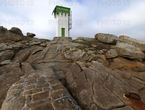 Green and white lighthouse on granite rocks