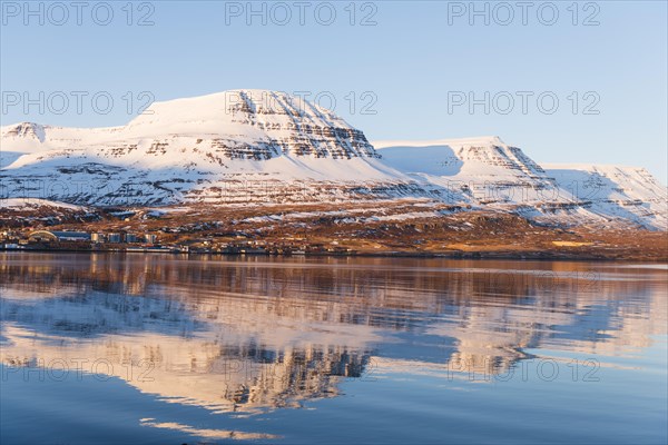 Water reflection of snow-covered mountains in a fjord