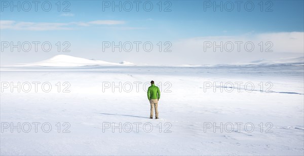 Young man stands alone in snowy landscape