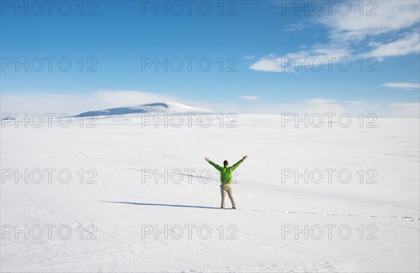 Young man stands alone in snowy landscape