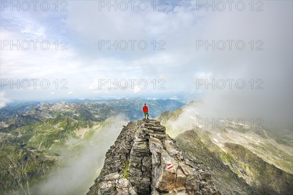 Hiker on the summit of the Hochgolling with rising fog