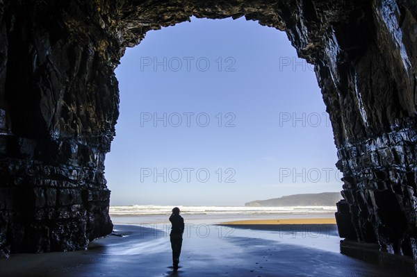 Woman standing in the giant entrance of Cathedral caves in backlit