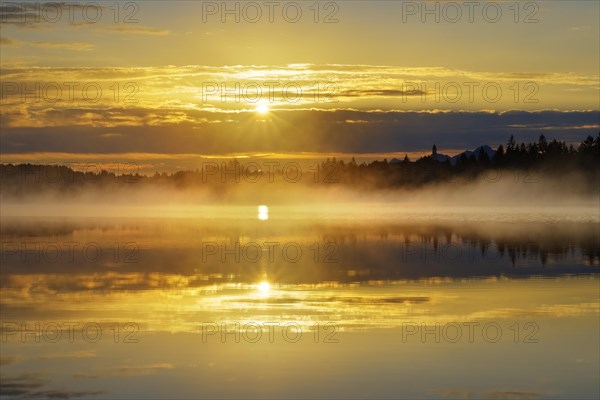 Sunrise with early morning mist over Kirchsee with Reutberg Monastery