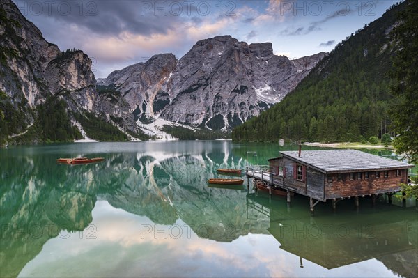 Green mountain lake with boats and boathouse