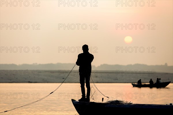Fisherman throws net in the sunrise on Ganges river