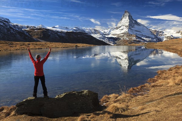 A woman stands with her arms outstretched on a rock