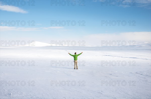 Young man stands alone in snowy landscape