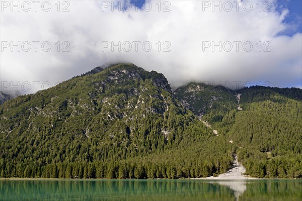 View over the emerald green lake Dobbiaco with mountain forest and Murengang