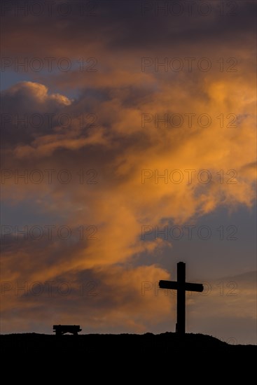 Summit cross with bank and dramatic clouds at sunrise