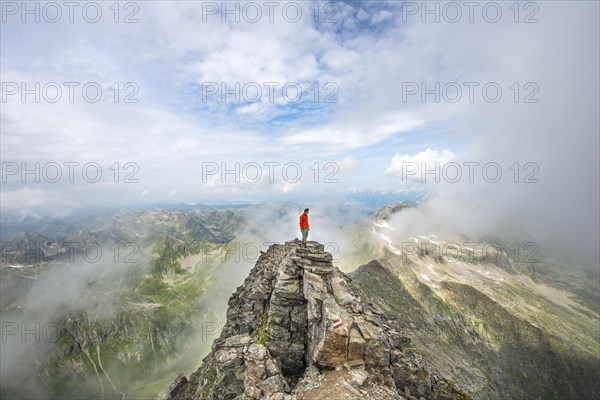 Hiker on the summit of the Hochgolling with rising fog