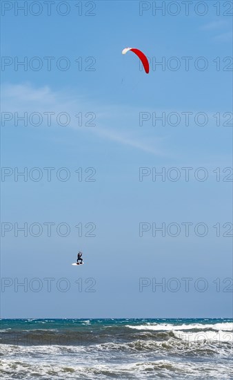 Kitesurfer in the air over sea with waves
