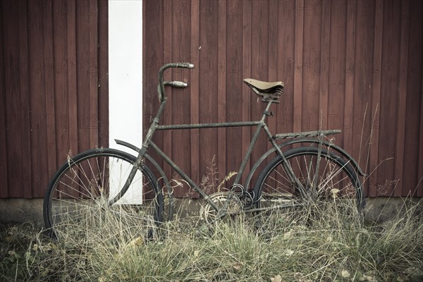 Old bicycle leans against a Swedish red wooden house