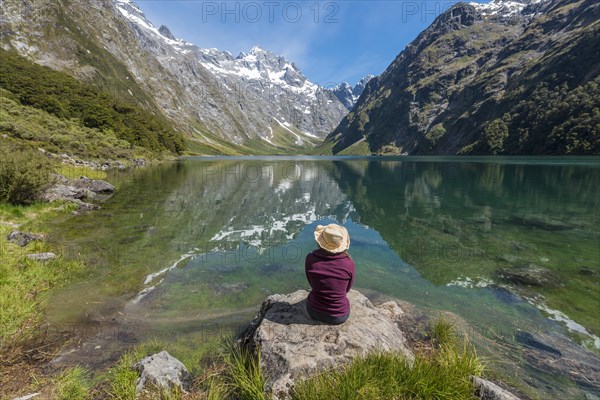 Female Hiker with sun hat sitting on shore