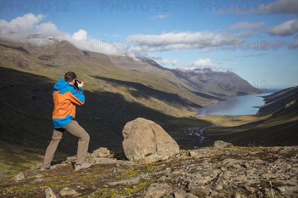 Photographer photographs view from Mjoafjaroarheioi Pass onto Mjoifjorour Fjord