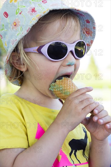 Toddler with sunglasses licking ice cream