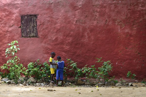 Two children in front of a red house facade