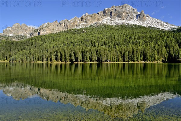 Mountain range Cadini di Misurina and dense mountain forest are reflected in Lake Misurina