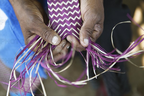 Hands of a woman weaving a mat