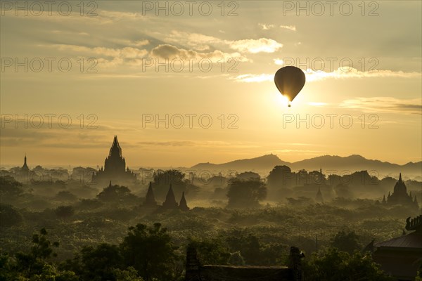 Hot air balloon at sunrise over temples and pagodas