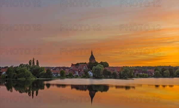 Cityscape with St. Nicholas' Church and lake Schulsee at sunset