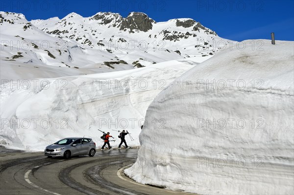 Car and two skiers in front of high snow walls