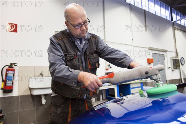 Coachbuilder master with the polishing machine on the car
