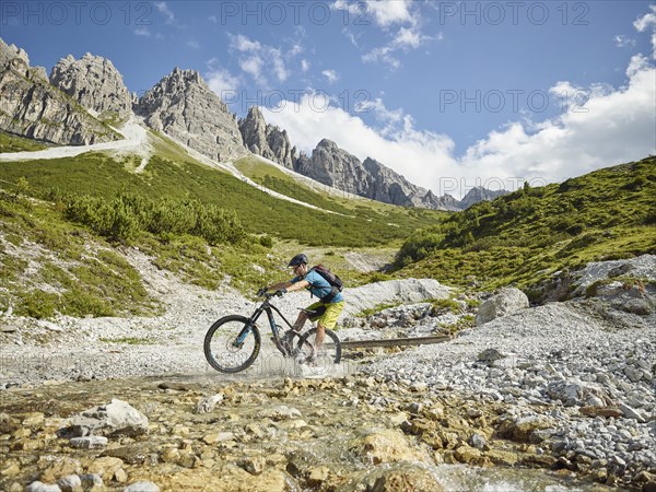 Mountainbiker rides with his mountain bike through a stream