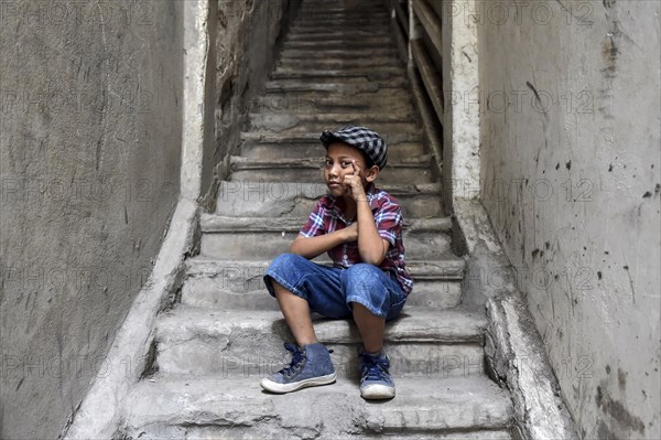 Boy on staircase with shirt and flat cap