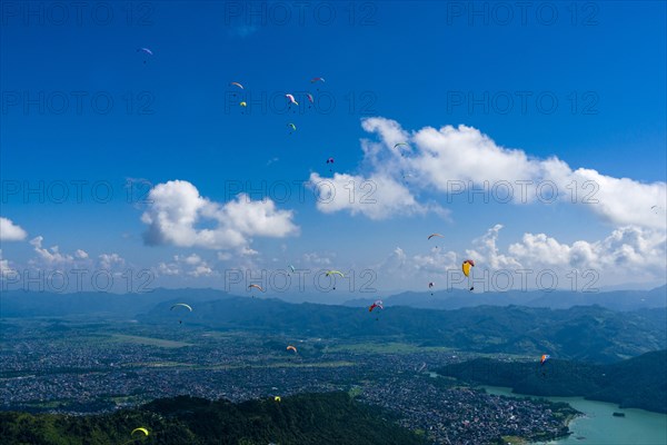 Many paragliders are flying over Pokhara and Phewa Lake