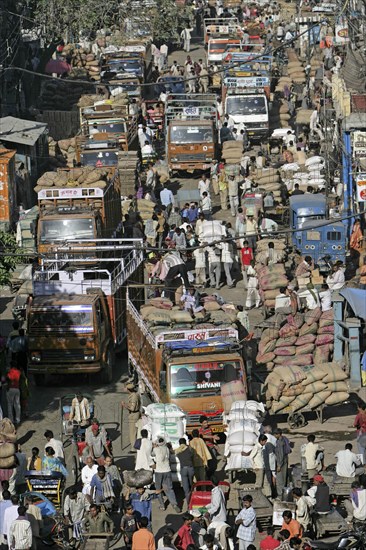 Merchants between trucks loaded with bags