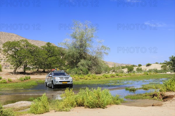 Off-road vehicle drives through Hoanib River