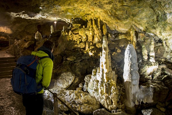 Young man looks at illuminated stalactites and stalacmites