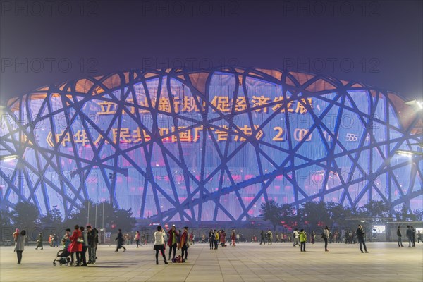 People on square in front of illuminated National Stadium in the Olympic Park