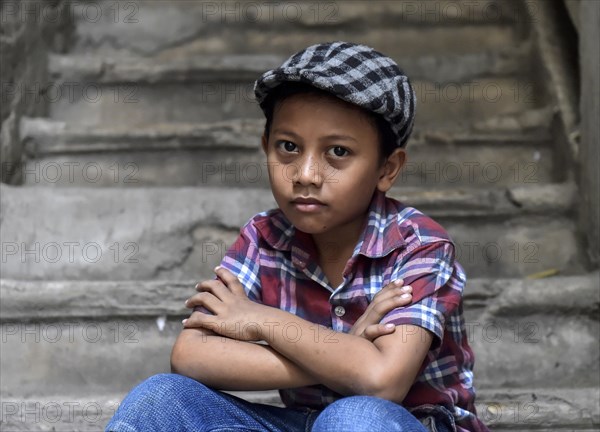 Boy on staircase with shirt and flat cap