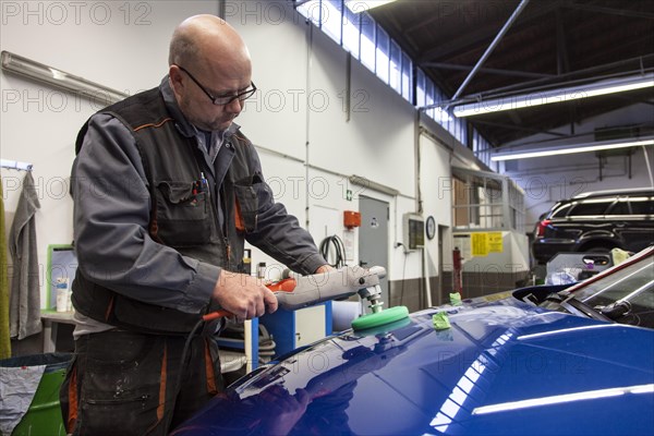 Coachbuilder master with the polishing machine on the car
