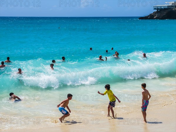 Tourists bathing in high waves at Maho Beach