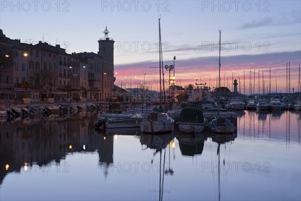 Old city with boats in the harbour at sunrise