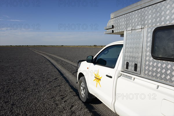 Truck with camper driving through Deception Pan in Deception Valley of the Central Kalahari Game Reserve