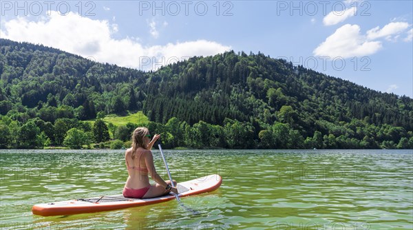 Young woman sitting on a Standup-Paddle Board or SUP