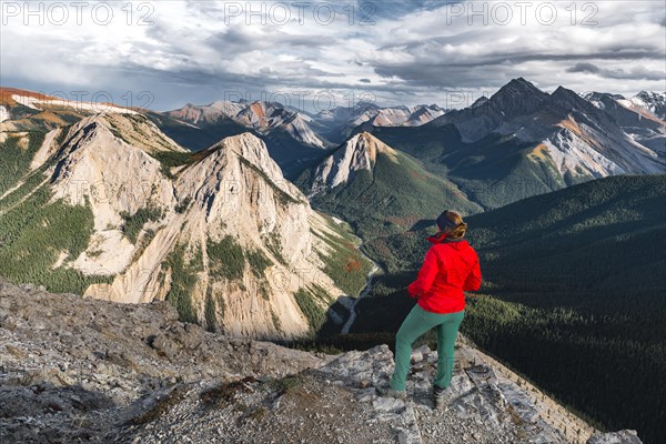 Female hiker looks from summit over mountain landscape